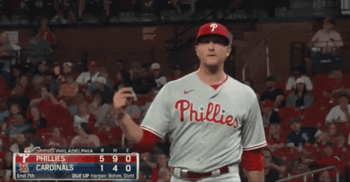 a phillies baseball player stands in front of the crowd