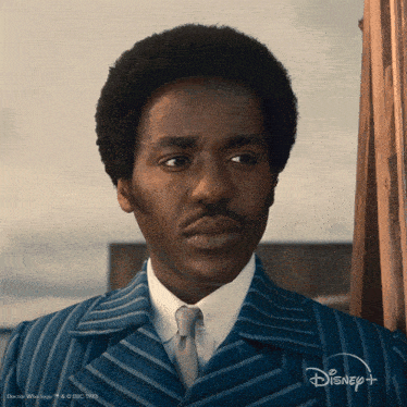 a man in a striped suit and tie is featured on disney plus