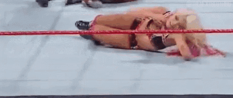 a female wrestler is laying on her back in a ring .