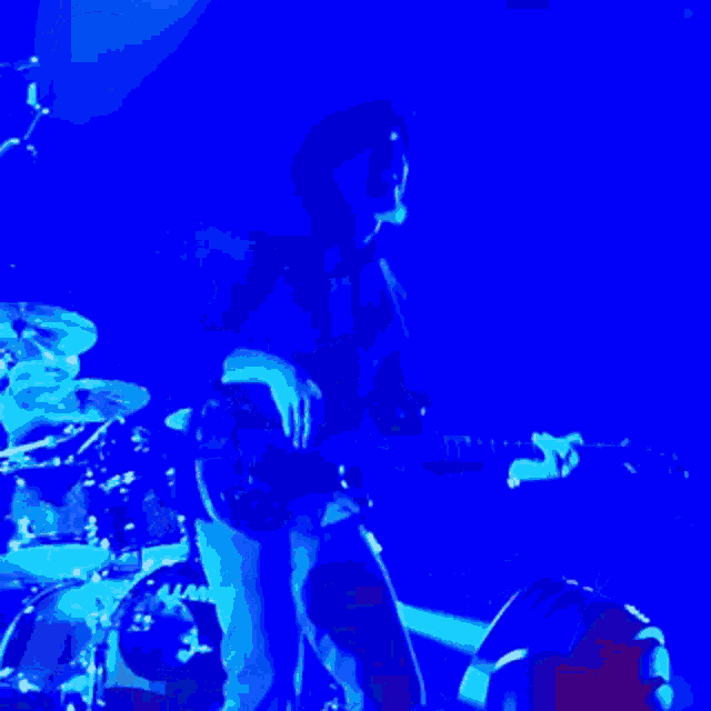 a man in a hat is playing a keyboard in front of a microphone