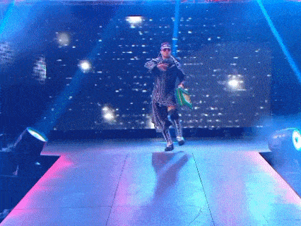 a wrestler is walking down a stage with a green bag