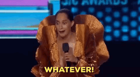 a woman in a gold dress is holding a microphone and saying whatever