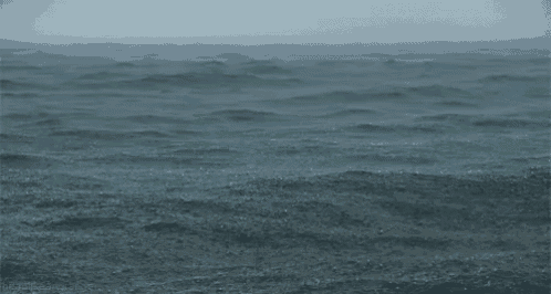 a large body of water with waves on a cloudy day