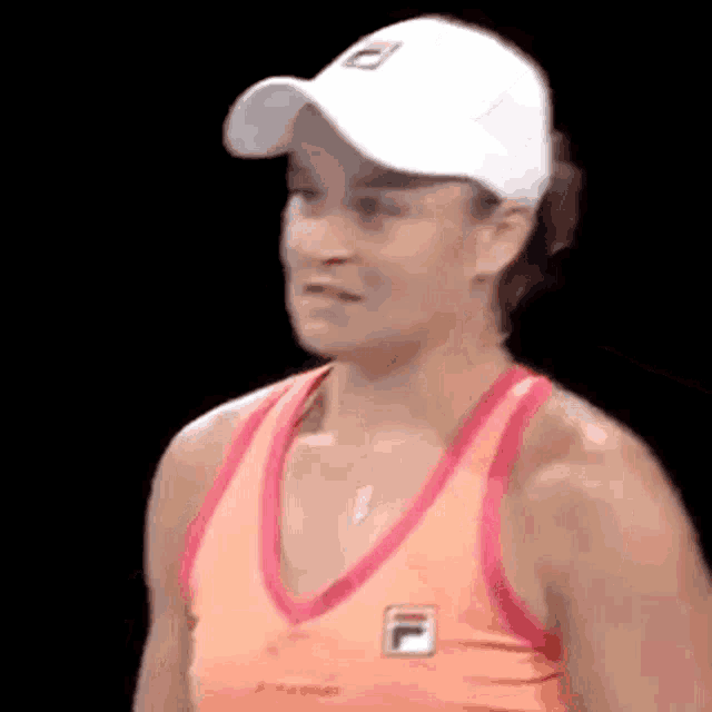 a woman wearing a white hat and an orange tank top is standing on a tennis court .