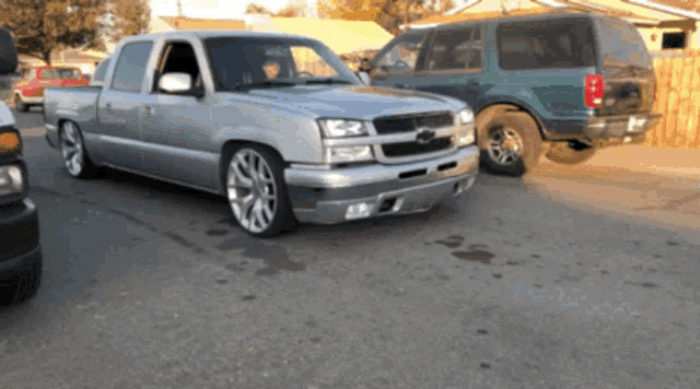a silver pickup truck is parked next to a green van
