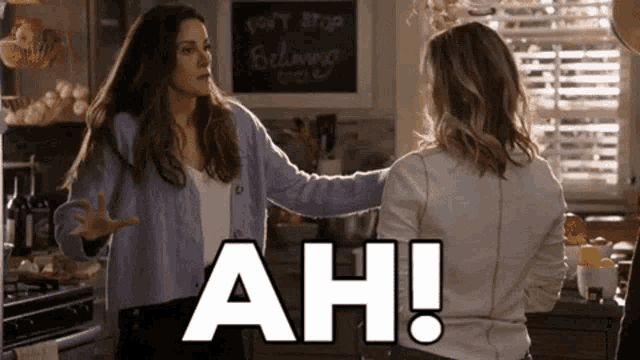 two women are having an argument in a kitchen and one of them says " ah "
