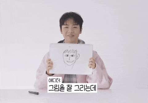 a person in a pink jacket holds up a drawing of a man 's face in front of their face