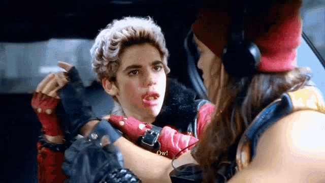 a boy with blood on his face is talking to a girl in a car