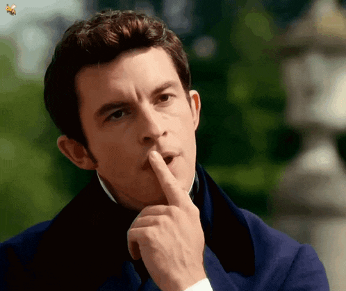 a man in a blue coat is holding his finger to his lips