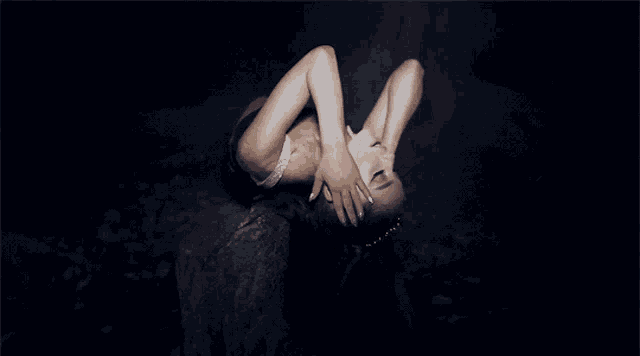a woman is laying upside down in the dark