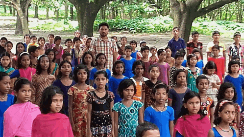 a man stands in front of a group of children in a park