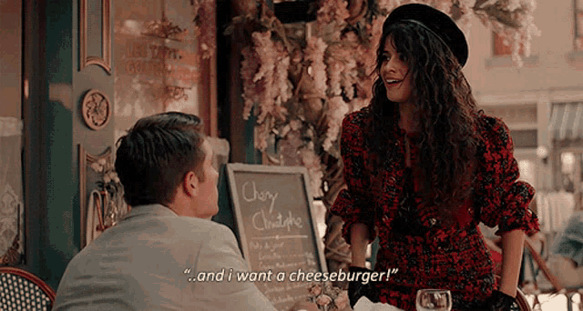 a man and a woman are sitting at a table in front of a sign that says " cherry chatte "