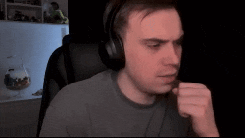 a man wearing headphones is sitting in a chair with his hand to his mouth