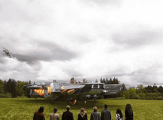 a group of people standing in a grassy field looking at a plane that says ' a ' on it