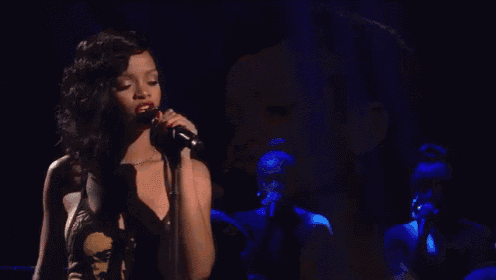 a woman singing into a microphone with red lipstick on her lips