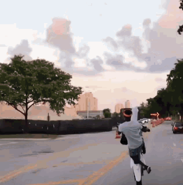 a man is riding a bike down a street with a city skyline in the background