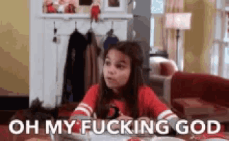 a little girl is sitting at a table with the words `` oh my fucking god '' written on her face .