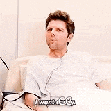 a man in a hospital gown is sitting on a couch and talking to someone .