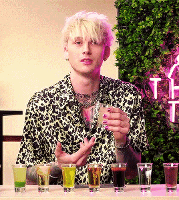 a man in a leopard print shirt holds a shot glass in his hand