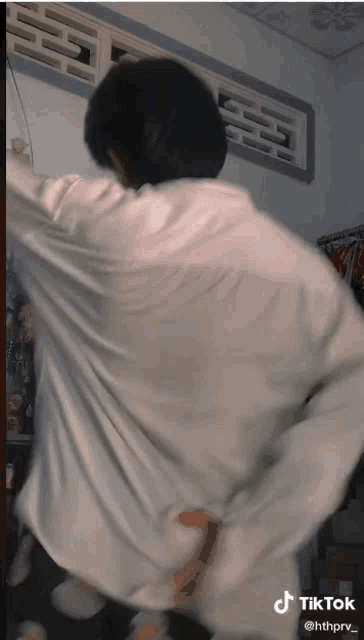 a man in a white shirt is dancing with a tiktok watermark on the bottom