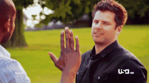 a man is giving another man a high five in a park .