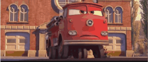 a red fire truck with a sad face is parked in front of a building