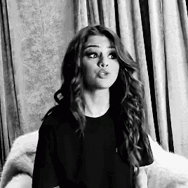a black and white photo of a woman with long hair making a funny face .