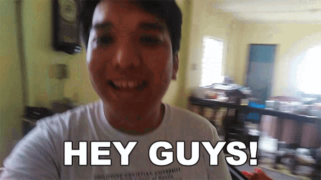 a man in a white shirt is smiling and says hey guys