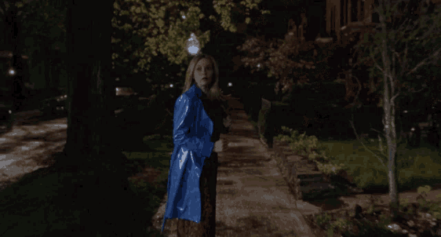 a woman in a blue coat is walking down a sidewalk