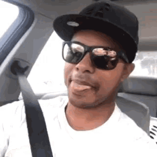 a man wearing sunglasses and a black hat is sticking his tongue out
