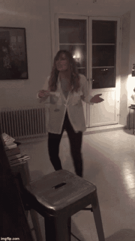 a woman in a white jacket is standing in a room