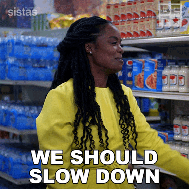 a woman in a yellow jacket is standing in a grocery store and saying we should slow down