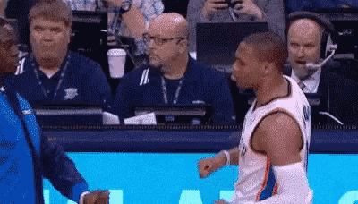 a basketball player is talking to a referee during a game while a crowd watches .