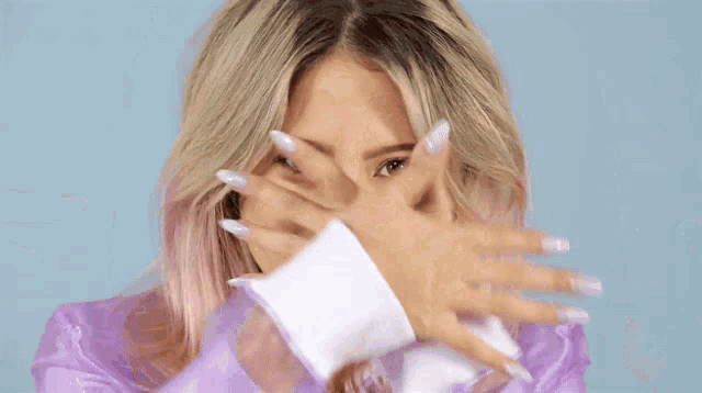 a woman covering her face with her hands with a blue circle behind her