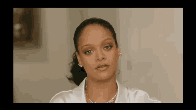 a close up of a woman 's face wearing a white shirt and a necklace .