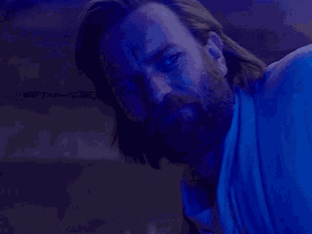 a man with a beard is smiling while holding a light saber