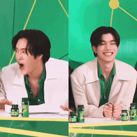 a man in a green shirt and white jacket is sitting at a table with bottles of pills on it