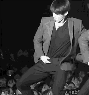 a black and white photo of a man in a suit dancing on a stage .