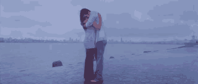 a man and a woman hugging each other on a beach