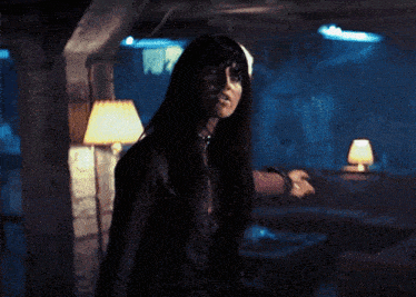 a woman in a dark room with a lamp