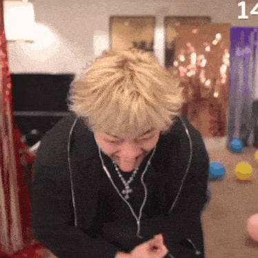a man with blonde hair is wearing headphones and a necklace with the number 14 on the bottom
