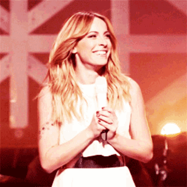 a woman in a white dress is holding a microphone