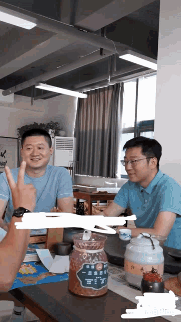 two men are sitting at a table with a jar that says ' chinese ' on the label