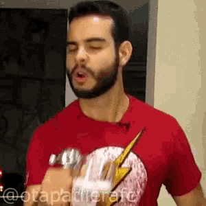 a man with a beard wearing a red t-shirt with a lightning bolt on it
