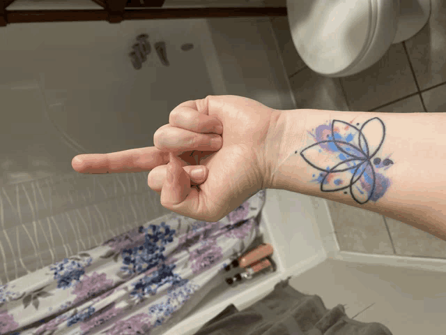 a person with a butterfly tattoo on their wrist is pointing