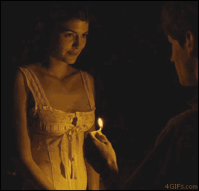 a naked woman looks at a man who is lighting a cigarette