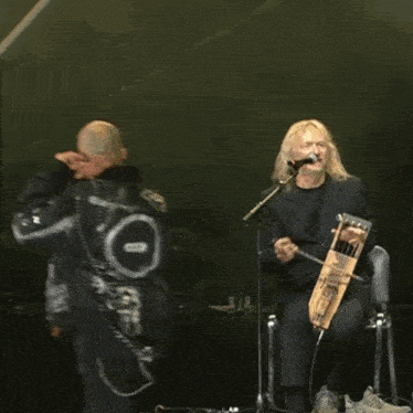 a man playing a harp and another man singing into a microphone on a stage