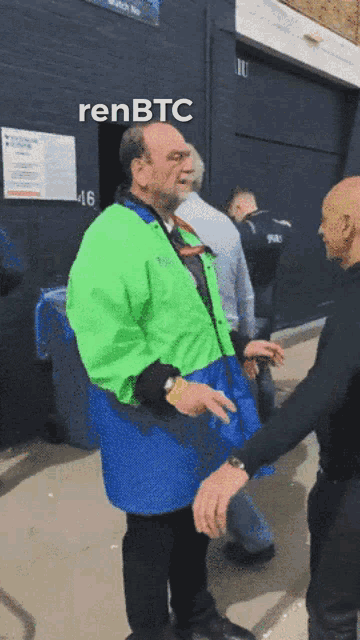 a man in a green jacket is talking to another man in a blue jacket