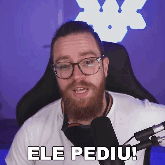 a man with glasses and a beard is sitting in front of a microphone and says ele pediu