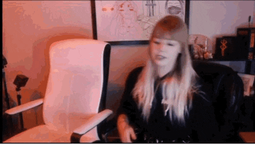 a woman is sitting in a chair in front of a computer monitor .